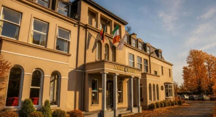 Elegant hotel entrance with flags, autumn trees, and inviting warm light