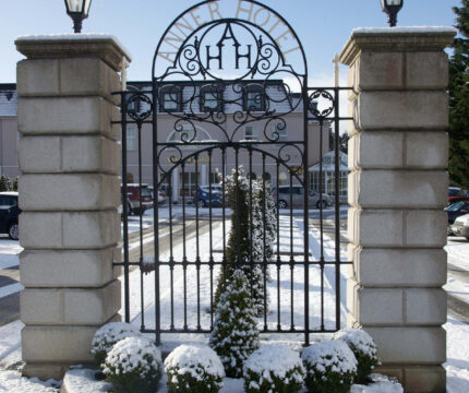Snow-covered entrance gate of The Anner Hotel in a winter setting.