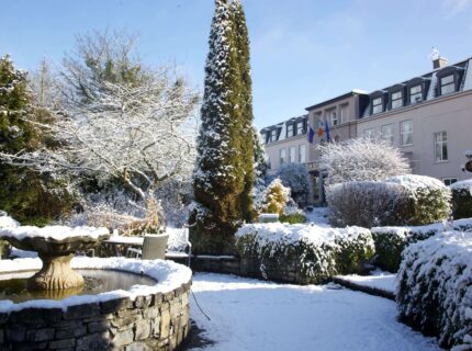 Snow-covered garden at The Anner Hotel, with a fountain and cosy winter atmosphere.