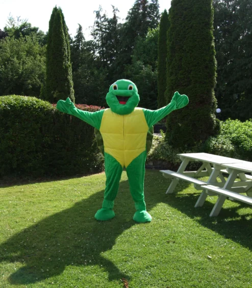 A friendly mascot in a turtle costume welcomes families in The Anner Hotel’s lush garden.