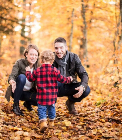 Family enjoying autumn stroll in vibrant forest.